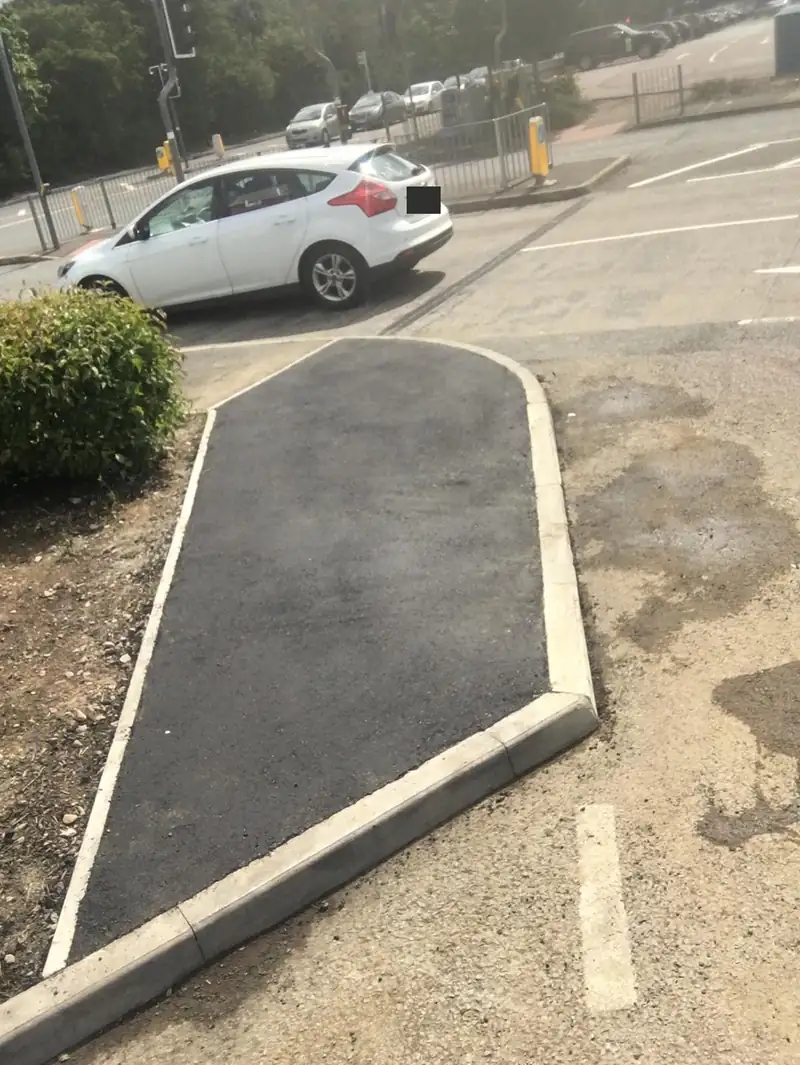 A tarmac bay with a concrete kerb edge in a car park