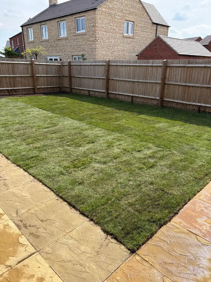 A newly turfed lawn beside a patio and a closeboard fence